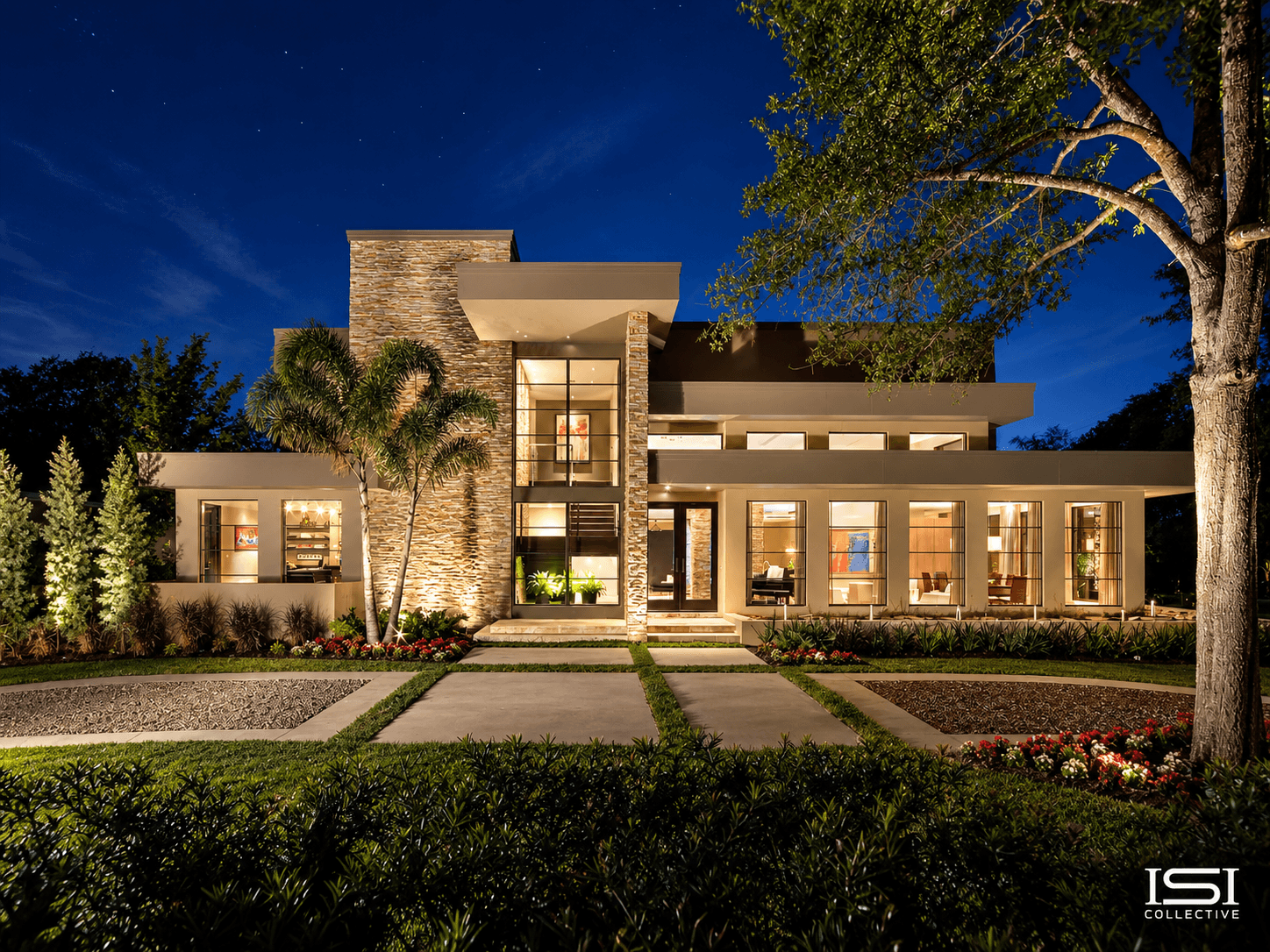 Completed luxury new construction home lit up at dusk with stone accents